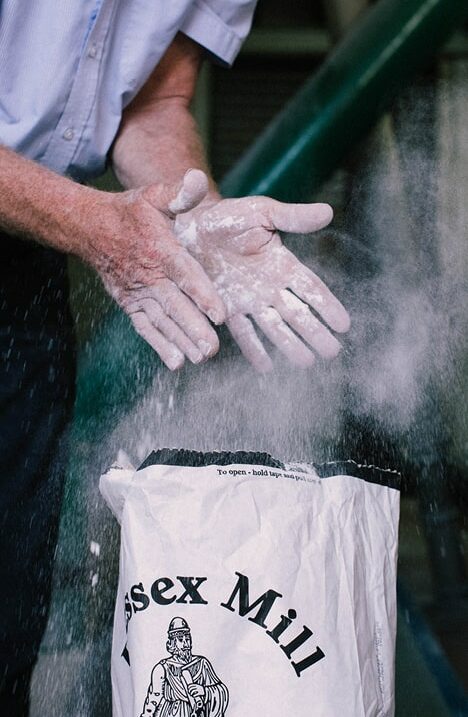 Man brushing flour off his hands after filling a sack
