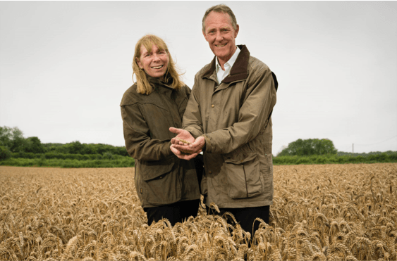 Doves Farm Foods founders Claire and Michael standing in wheat field